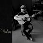 "Wandered. Jack Rutter." Ein Mann sitzt mit Gitarre in einem dunklen Raum, trägt eine Mütze und schaut nach rechts.