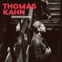 Text: "THOMAS KAHN UNDERTONES". Ein Mann im Profil, mehrfach in Spiegeln reflektiert, trägt eine Jacke und Mütze.