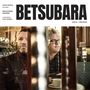 Text: BETSUBARA. Personen in einem Café; links Mann mit Bart, rechts Mann mit Brille, entspannte Atmosphäre.