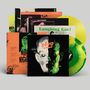 Stapel von Vinyl-Schallplatten und Hüllen mit Texten wie "DEVO", "NITE", "Laughing Gas!" in einem retro-futuristischen Stil.