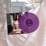 Die Texte: "JOSEFIN ÖHRN CHERRY". Eine Frau in einem glänzenden, gold-rosafarbenen Kleid, mit einer lila Schallplatte.