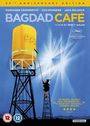 "Bagdad Café" 30th Anniversary Edition. Gelber Wasserturm, Person auf Leiter, blauer Himmel.