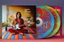 Texte: "Clowns and Jugglers", "Syd Barrett". Person sitzt mit Gitarre auf farbigem Boden. Bunte CDs mit psychedelischen Mustern.