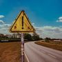 "James Marriott" und "Warning Signs" stehen in weiß. Ein gelbes Dreieck mit Ausrufezeichen an einer Landstraße.