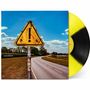 Texte: "James Marriott", "Warning Signs". Gelbes Warnschild mit Ausrufezeichen an einer Landstraße, blauer Himmel.