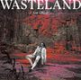 "WASTELAND" und "Jim Ghedi" stehen im Vordergrund. Eine Person sitzt vor einer steinigen, rötlich gefärbten Felskulisse.