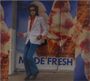 Text "MADE FRESH". Eine Person mit weißem Sakko und blauer Hose steht vor großen Eiswaffeln.