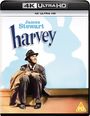 James Stewart; harvey. Ein Mann in Anzug und Hut sitzt lächelnd neben einem Schatten in Hasenform.