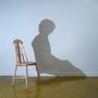 Kein Text vorhanden. Ein leerer Stuhl wirft den Schatten einer sitzenden Person an eine Wand.