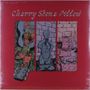 "Cherry Stone Pillow". Rotes Layout mit drei illustrativen Panels: Blumen und Musiknoten, Statue, Steine und Objekte.