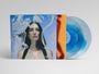 Auf einem blauen Hintergrund steht eine Frau mit dunklen Haaren. Links und rechts sind ein oranger Streifen und eine blaue Vinyl-Schallplatte zu sehen.