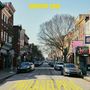 Oben steht "HEAVENS EDGE", unten "PHILADELPHIA". Eine städtische Straße mit Autos und Backsteingebäuden.