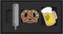 Text "MOLESKINE" auf silbernem Metall. Illustrationen: Brezel mit Kristallen, Bierkrug mit Schaum in schwarzem Etui.