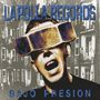 Text: "LAPOLLA RECORDS" und "BAJO PRESION". Illustration eines Mannes mit VR-Brille vor Gebäuden.