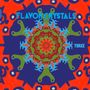 "FLAVOR CRYSTALS" und "THREE" in Blau. Bunte, symmetrische Mandala-Illustration mit kräftigen Farben und Mustern.