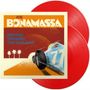 "JOE BONAMASSA" und "DRIVING TOWARDS THE DAYLIGHT". Illustration: Blaues Rennauto, Palmen, zwei rote Schallplatten.