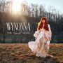 Text: "WYNONNA The Hard Truth". Eine Frau mit rotem Haar in einem langen weißen Kleid steht auf einem Feld bei Sonnenuntergang.