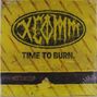 „TIME TO BURN.“ Ein ovales Logo mit stilisiertem Text „XCOMA“ auf gelbem Hintergrund mit diagonalen Linien.