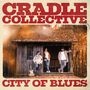 "CRADLE COLLECTIVE" und "CITY OF BLUES" in großen Buchstaben. Drei Männer vor einer Holzhütte im herbstlichen Wald.