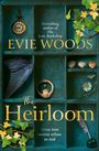 Ein Regal mit einer alten Uhr, Muscheln, einem Federkiel, Efeu und einem Flügel. "Evie Woods - The Heirloom" steht groß geschrieben.