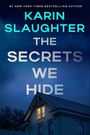 Der Text sagt: "Karin Slaughter, The Secrets We Hide". Ein beleuchtetes Fenster in einem Hausdach bei Nacht.