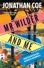 „Mr Wilder & Me“ von Jonathan Coe. Frau in gelbem Tuch schaut auf pastellfarbene Gebäude am Strand, Filmdreh im Gange.