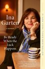 „Ina Garten, a memoir: Be Ready When the Luck Happens.“ Frau mit blauem Schal, lächelt, stützt Kopf auf Hand, Tasse auf Tisch.