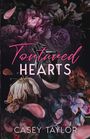 "Tortured Hearts" und "Casey Taylor". Illustration: Blumen, ein stilisiertes schwarzes Herz und fallende Blütenblätter.