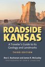 "ROADSIDE KANSAS: A Traveler’s Guide..." Ein Auto auf staubiger Straße, im Hintergrund beeindruckende Felsformationen.