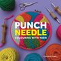 "PUNCH NEEDLE COLOURING WITH YARN" steht auf einem runden Stickrahmen mit buntem Garn. Werkzeuge und Wollknäuel sind darum verteilt.