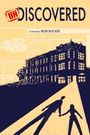 Text im Bild: "UNDISCOVERED", "A Novel by BOB BUCKEL", "Mother, Baby Survive Icy Crash". Illustration einer Silhouette vor Gebäude.