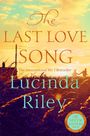 "The Last Love Song" von Lucinda Riley, ein Bestseller. Hintergrund: Sonnenuntergang, Silhouetten eines Paares in Wiese.