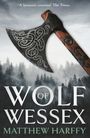 "Wolf of Wessex" von Matthew Harffy. Eine Axt mit keltischem Muster und Wald im Hintergrund.