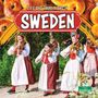 "Life and Traditions in Sweden." Vier Personen in traditionellen Kostümen spielen Geigen und gehen einen Weg entlang.