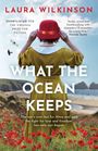 "WHAT THE OCEAN KEEPS" zeigt eine Person mit rotem Hut und gelbem Kleid, die das Meer und Klippen betrachtet, umgeben von Mohnblumen.