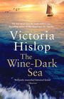 „The Wine-Dark Sea“ von Victoria Hislop. Ein Segelboot vor Sonnenuntergang auf einem ruhigen Meer mit fliegenden Vögeln.