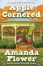 „Cover to be revealed soon!“, „APPLE CORNERED“, „by Amanda Flower“. Unten ein stilisiertes Logo mit einem blauen Buch.