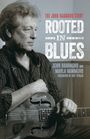 Text: "THE JOHN HAMMOND STORY ROOTED IN BLUES JOHN HAMMOND AND MARLA HAMMOND FOREWORD BY ART TIPALDI".  
Ein Mann hält eine Gitarre.