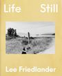 „Life Still“ und „Lee Friedlander“ in großer Schrift auf gelbem Hintergrund, Foto von Landschaft mit „HOPE auto repair“-Schild.