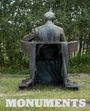 Text: „MONUMENTS“. Eine verwitterte Statue eines sitzenden Menschen von hinten, in einer grünen Umgebung.