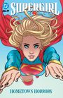 "SUPERGIRL", "HOMETOWN HORRORS", DC-Logo. Illustration einer fliegenden Superheldin mit blondem Haar und rotem Umhang.