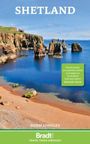 "Shetland", Zitat von Michael Palin über Bradt Guides. Küstenlandschaft mit Felsen und blauem Meer bei klarem Himmel.
