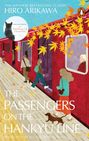 Text: "Hiro Arikawa, The Passengers on the Hankyu Line." Illustration eines roten Zuges mit Passagieren und herbstlichen Blättern.