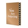 "You Are Amazing" steht auf einer braunen Ordnerfront. Der Rand zeigt ein Zickzackmuster in Schwarz und Weiß.