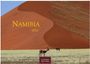 „Namibia 2027, Casares Edition“. Zwei Antilopen stehen vor einer großen roten Sanddüne unter blauem Himmel.