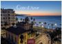 "Cote d'Azur", "2027", "CASARES EDITION". Küstenlandschaft bei Sonnenuntergang mit Gebäuden, Straße und Palmen.