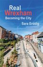 „Real Wrexham: Becoming the City“ von Sara Erddig. Ein leerer Stadtweg mit roten Backsteinhäusern und blauem Himmel.