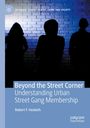 "Beyond the Street Corner: Understanding Urban Street Gang Membership" von Robert F. Hesketh. Drei Personen in Silhouetten vor Ziegelmauer.