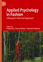"Applied Psychology in Fashion: A Research-Informed Approach", rote Schrift oben, Waldhintergrund, rote Kleidung in Bäumen.