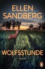 Text: „ELLEN SANDBERG“, „WOLFSSTUNDE“, „ROMAN“. Ein Reh steht auf einem Feld, im Hintergrund ein Sonnenuntergang und Gebäude.